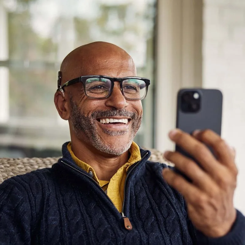 A man smiling while using his smartphone